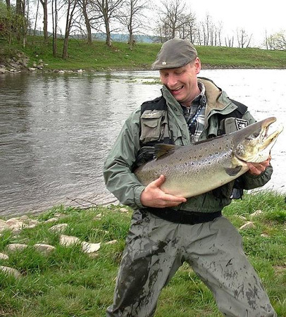 Thomas Berntsson med en grann nystigen hanlax vikt 11,0 kg fångad den 30 april 2008 på fluga (enhandsspö). Sträckan i bakgrunden är zon 3 på Kullagård.